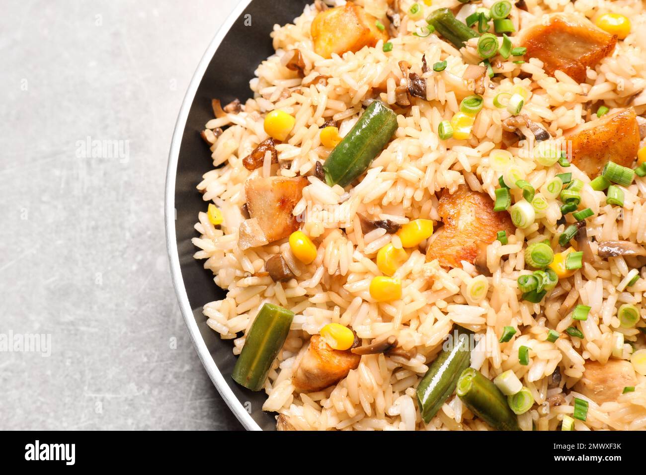 Delicious rice pilaf with chicken and vegetables on light grey table