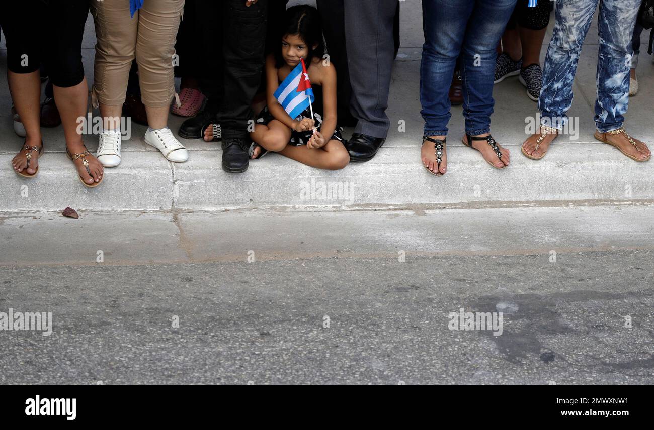 A girl holds a Cuban flag as she waits with others waits the arrival of
