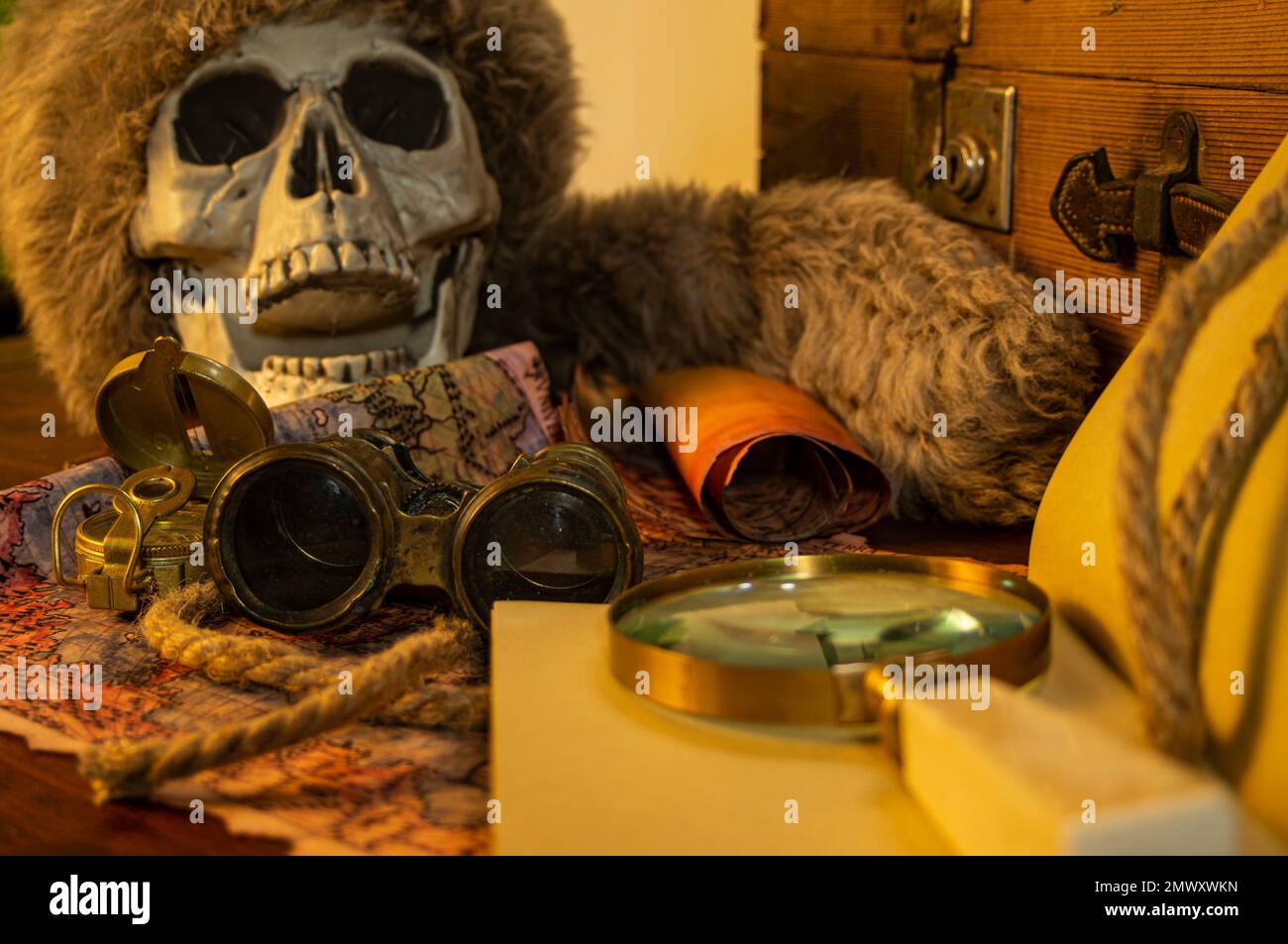 Antique adventure scroll background on adventurer table and next to skull skull: Binoculars, scroll, rope, candle and compass on the table. Stock Photo