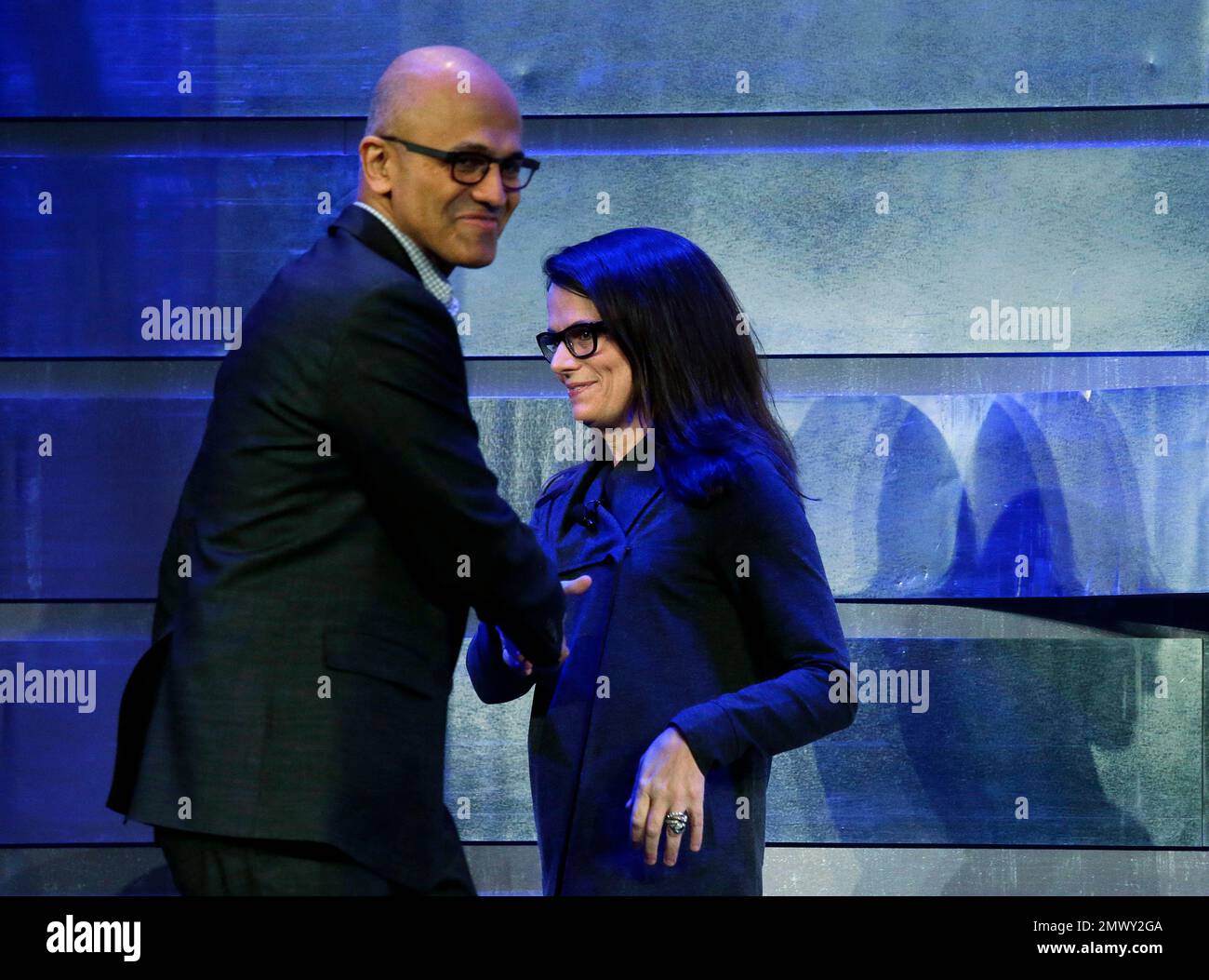 Microsoft CEO Satya Nadella, left, shakes hands with Amy Hood, chief