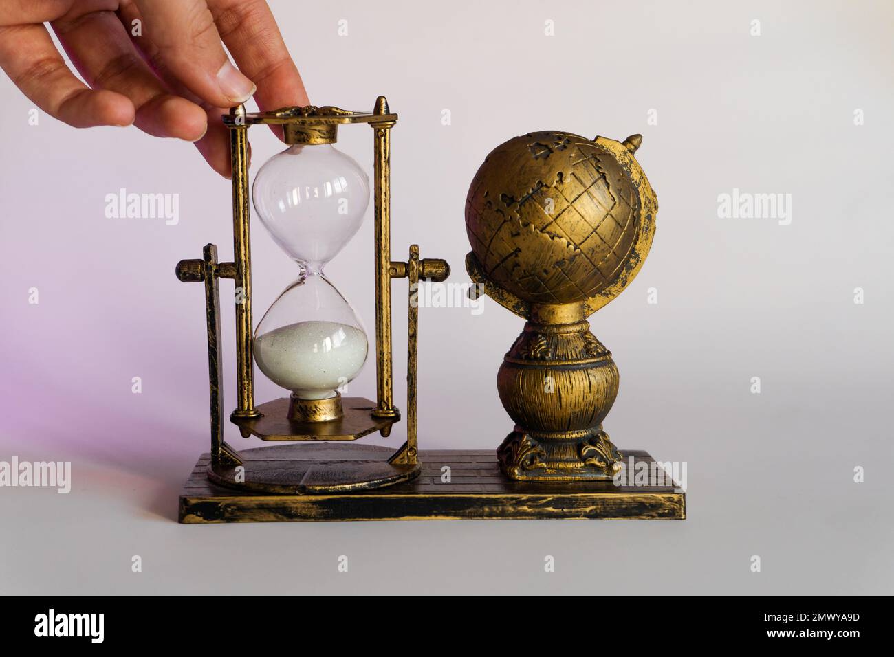 Hourglass held in hand. Earth and Hourglass. The symbolism of hourglasses. Stock Photo