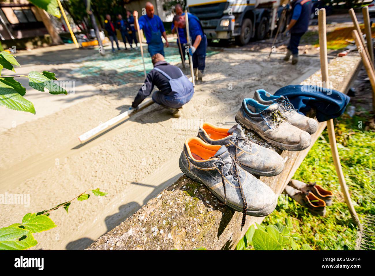 Old worn out safety shoes lined, placed on small wall near construction