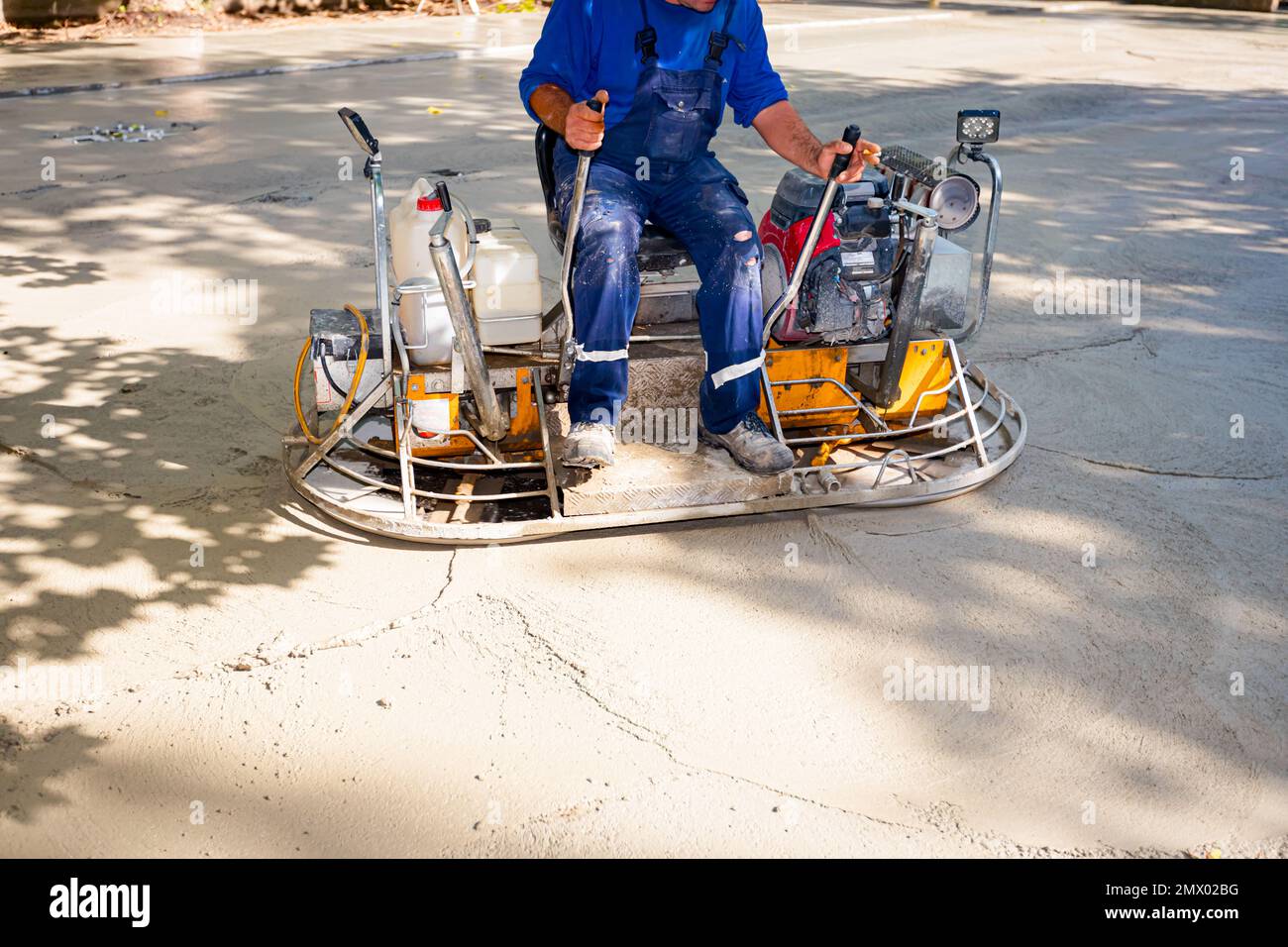 Worker sitting on a selfleveling power trowel machine with gas engine