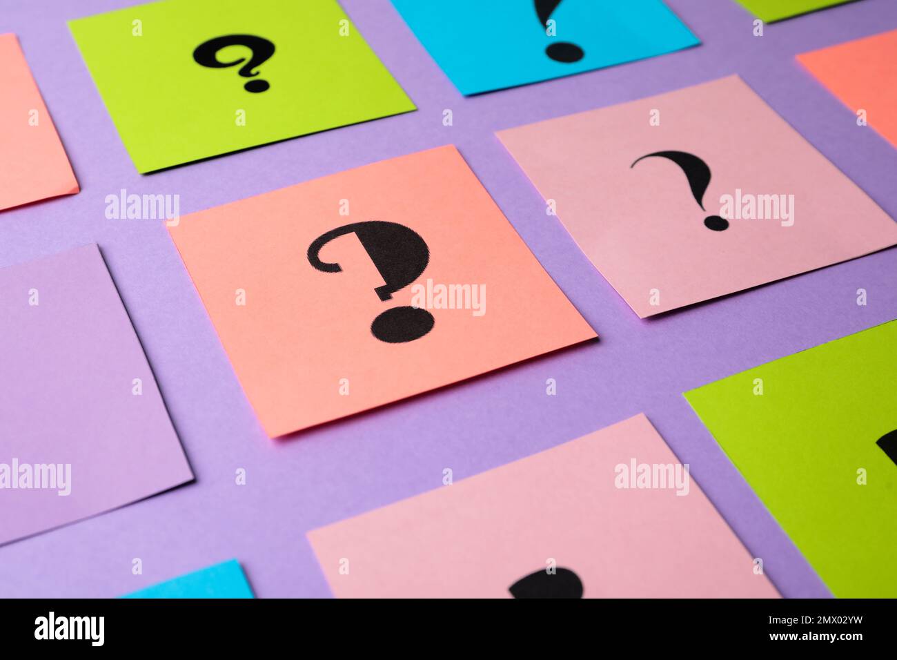 Paper cards with question marks on violet background, closeup Stock