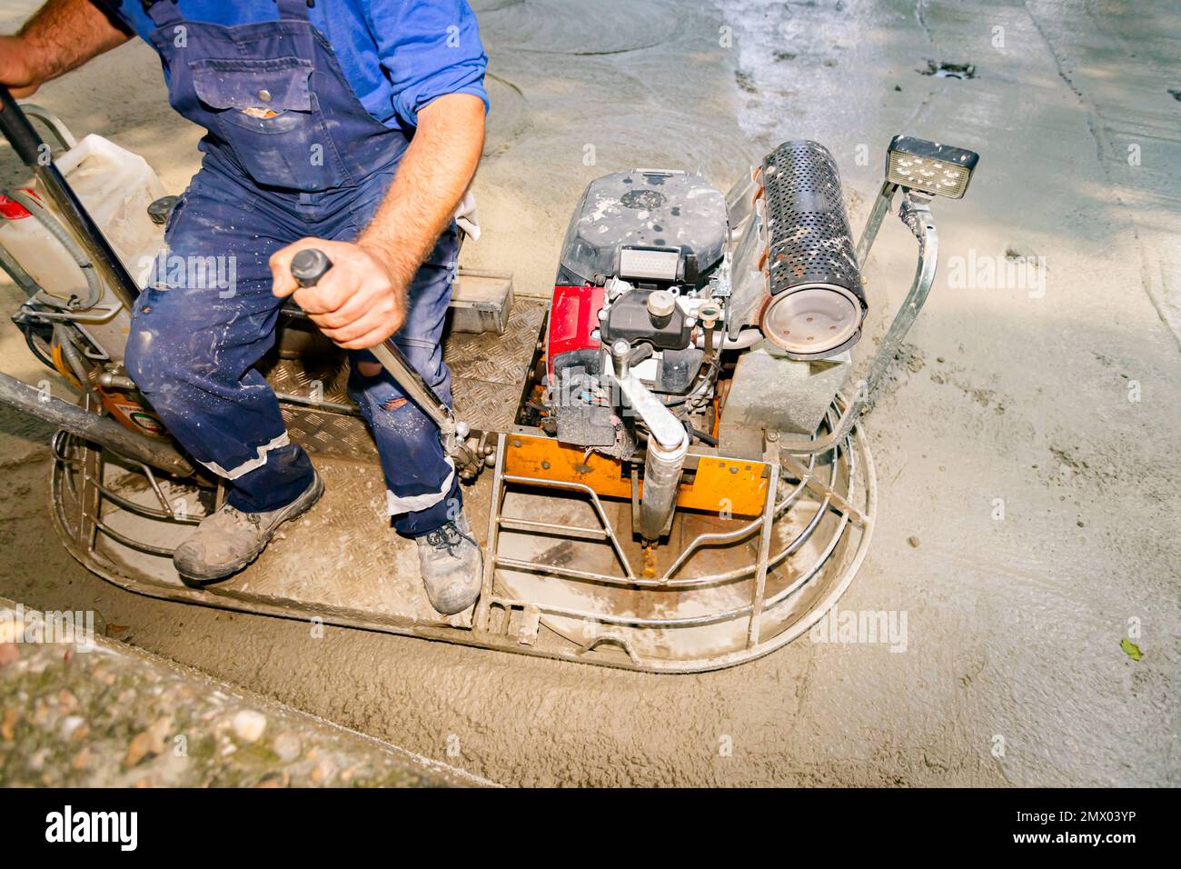 Worker sitting on a selfleveling power trowel machine with gas engine
