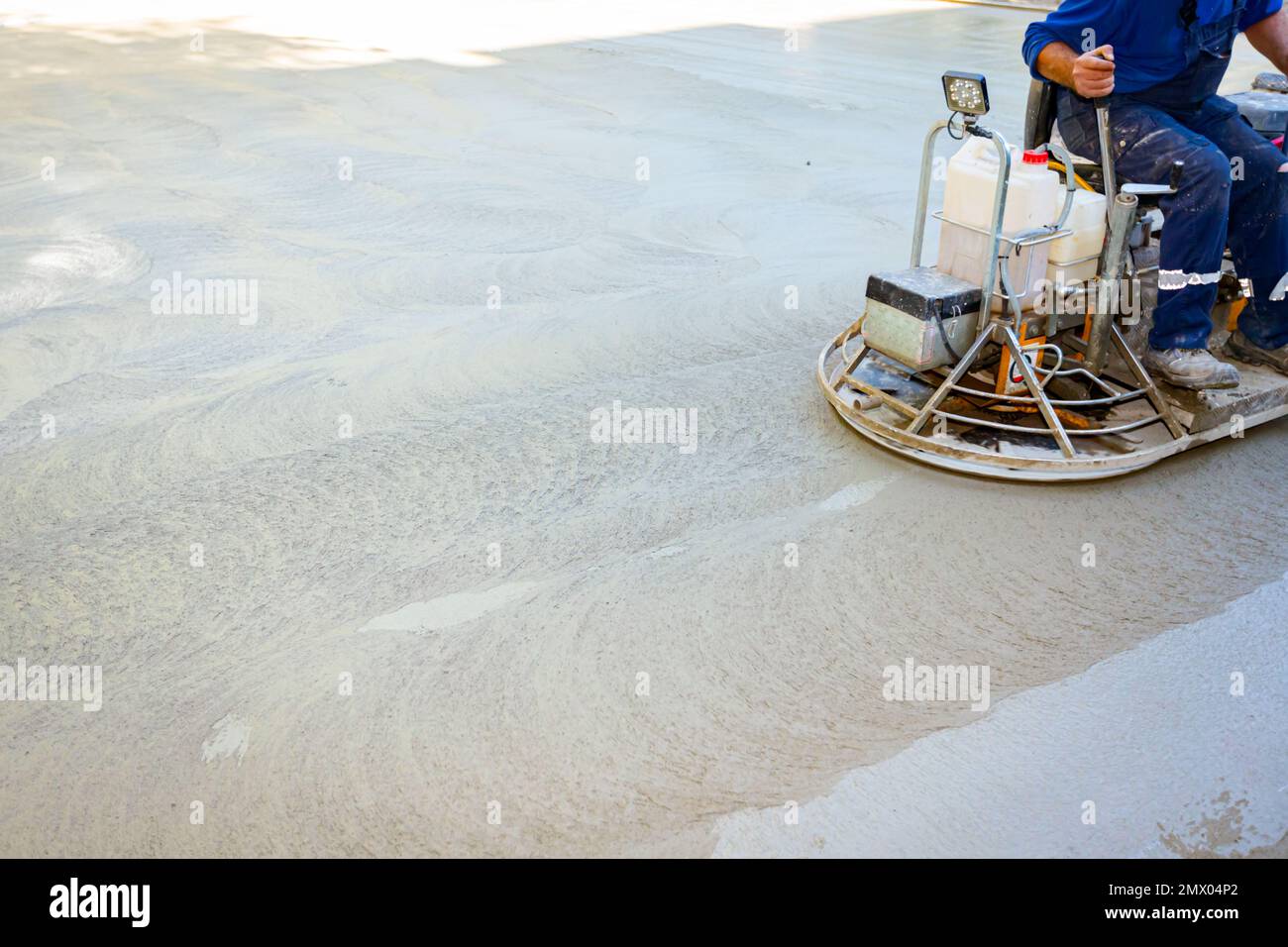 Worker sitting on a selfleveling power trowel machine with gas engine
