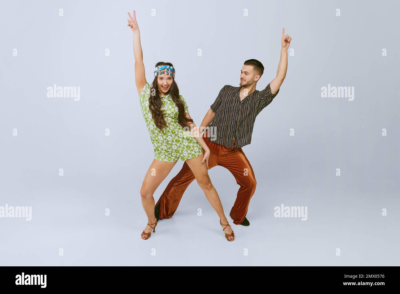 Stylish emotional young man and woman in fashionable retro outfits dancing disco dance isolated over grey studio background Stock Photo