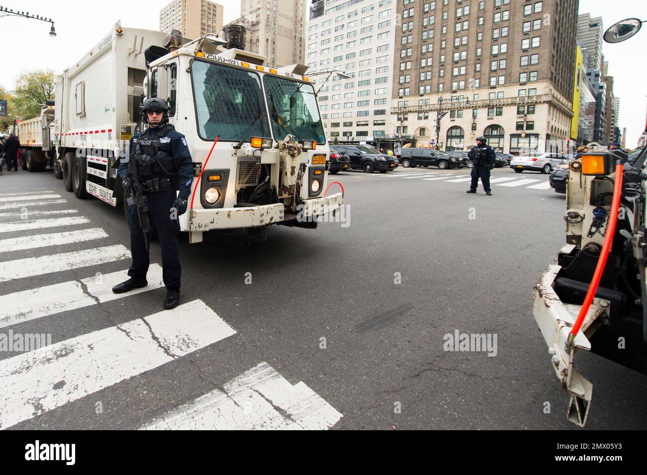 An NYPD police officer stands guard in front of garbage trucks on 59th