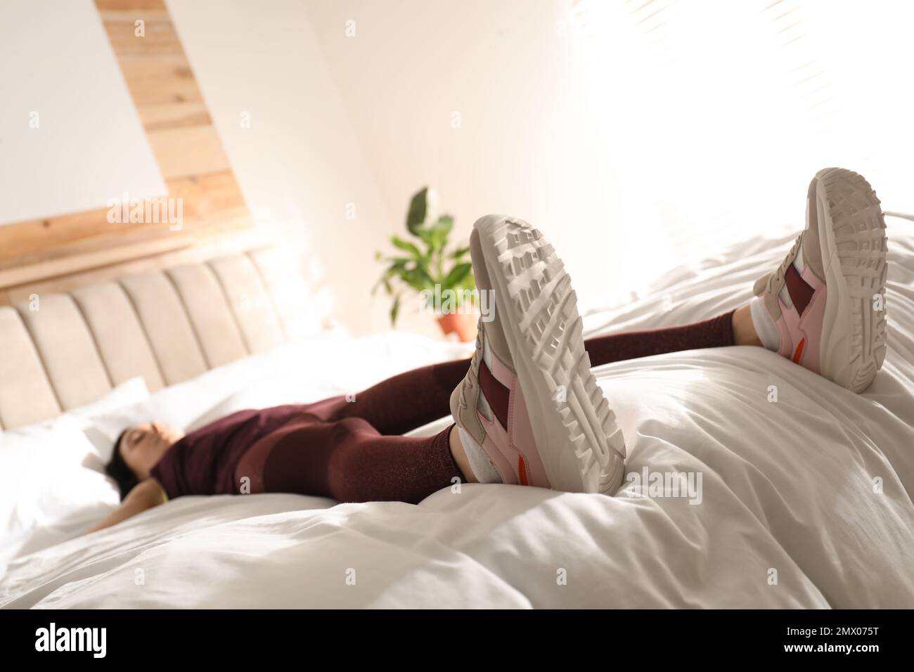 Lazy young woman sleeping on bed instead of morning training, focus on