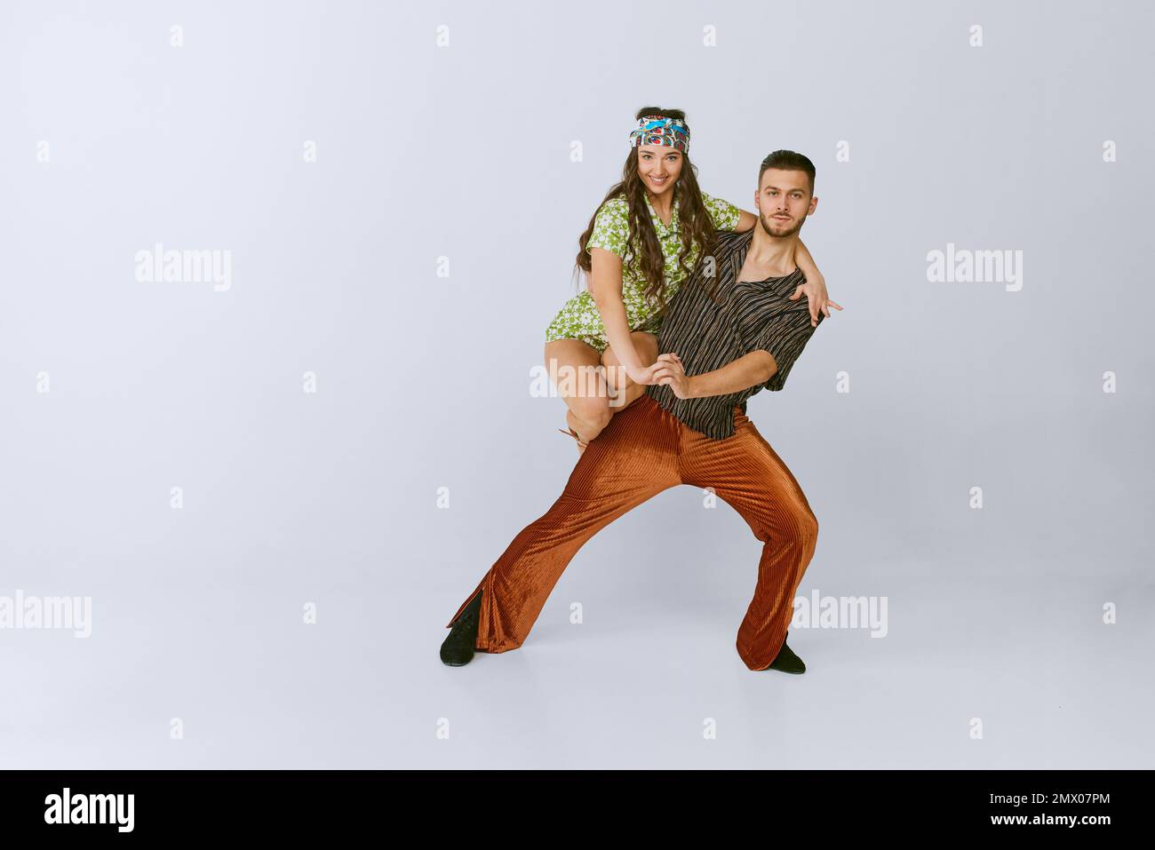 Impressive position. Beautiful. talented young man and woman, disco dancers dancing isolated over grey studio background. American culture, hobby Stock Photo
