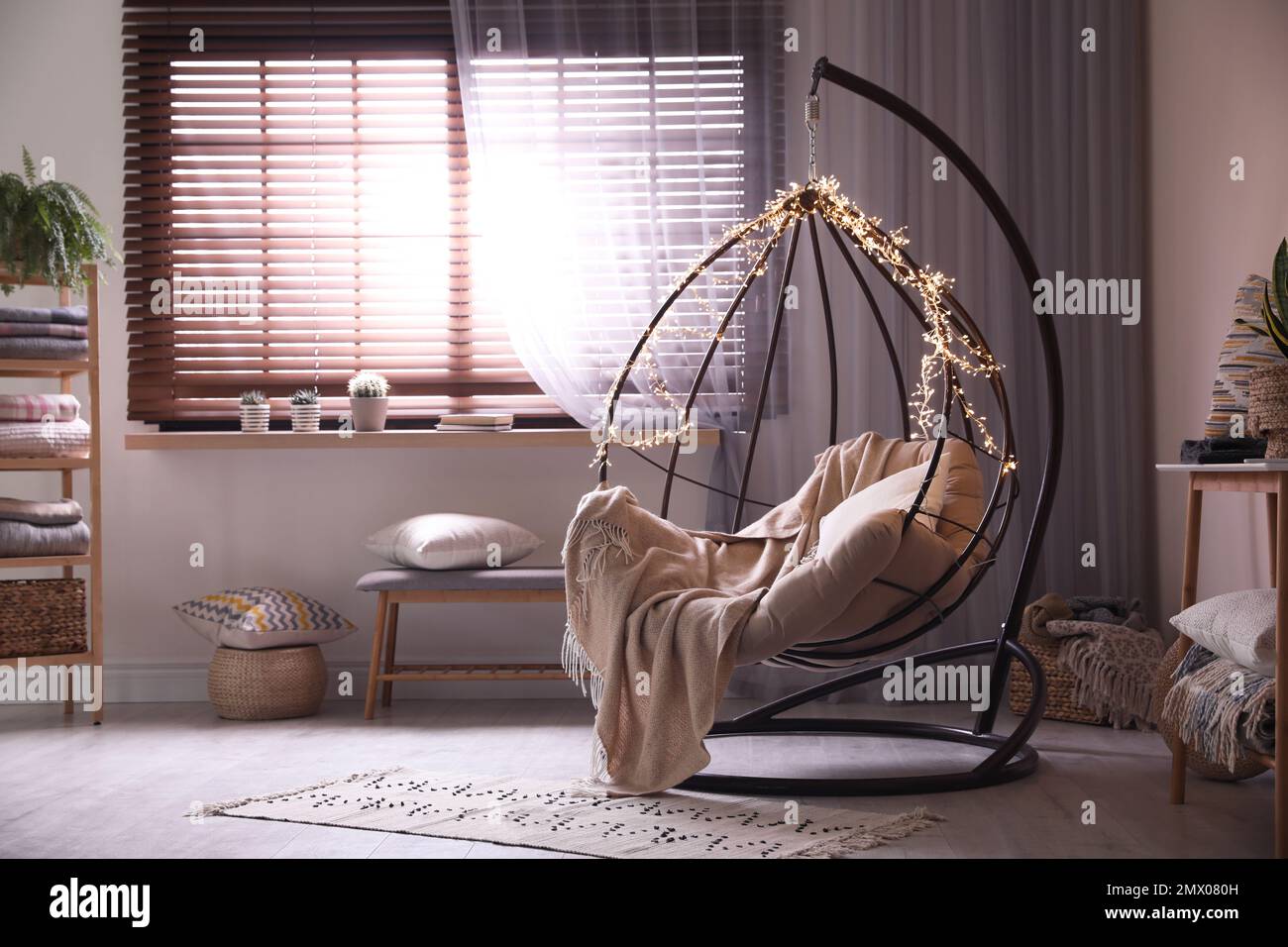 Cozy hanging chair with fairy lights in modern living room. Interior design Stock Photo Alamy