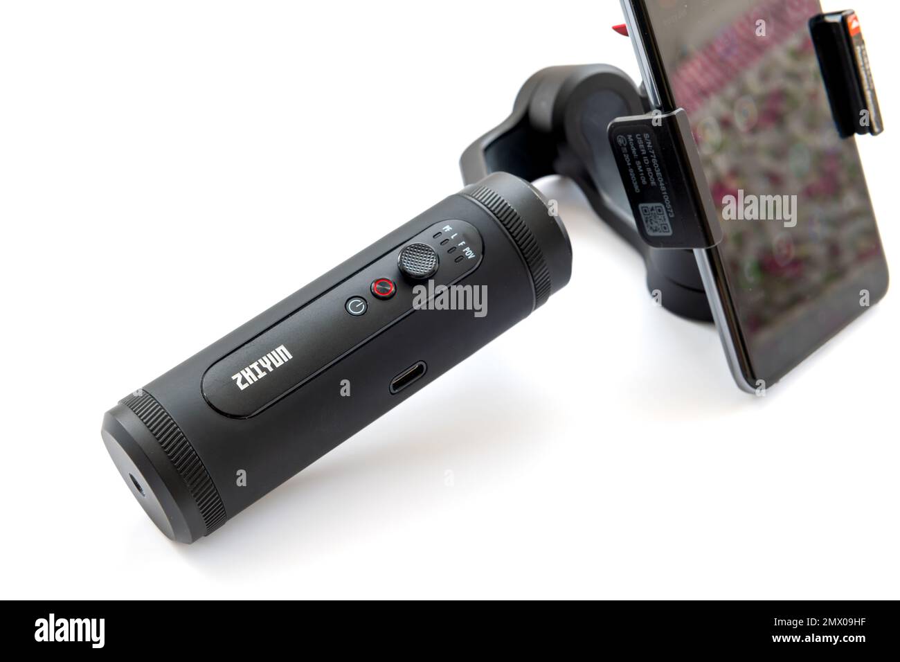 London. UK- 02.01.2023. A Zhiyun handheld gimbal stabilizer with a smart phone attached isolated in white. Stock Photo