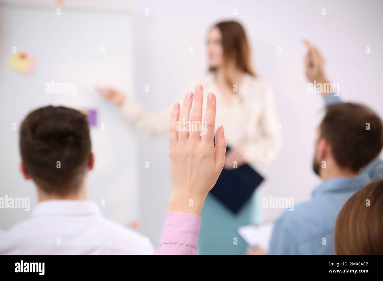 Woman raising hand to ask question at business training indoors, closeup Stock Photo
