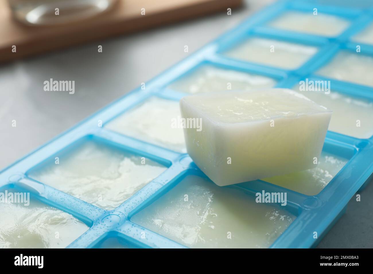 Ice cube tray with frozen milk on grey table, closeup Stock Photo - Alamy