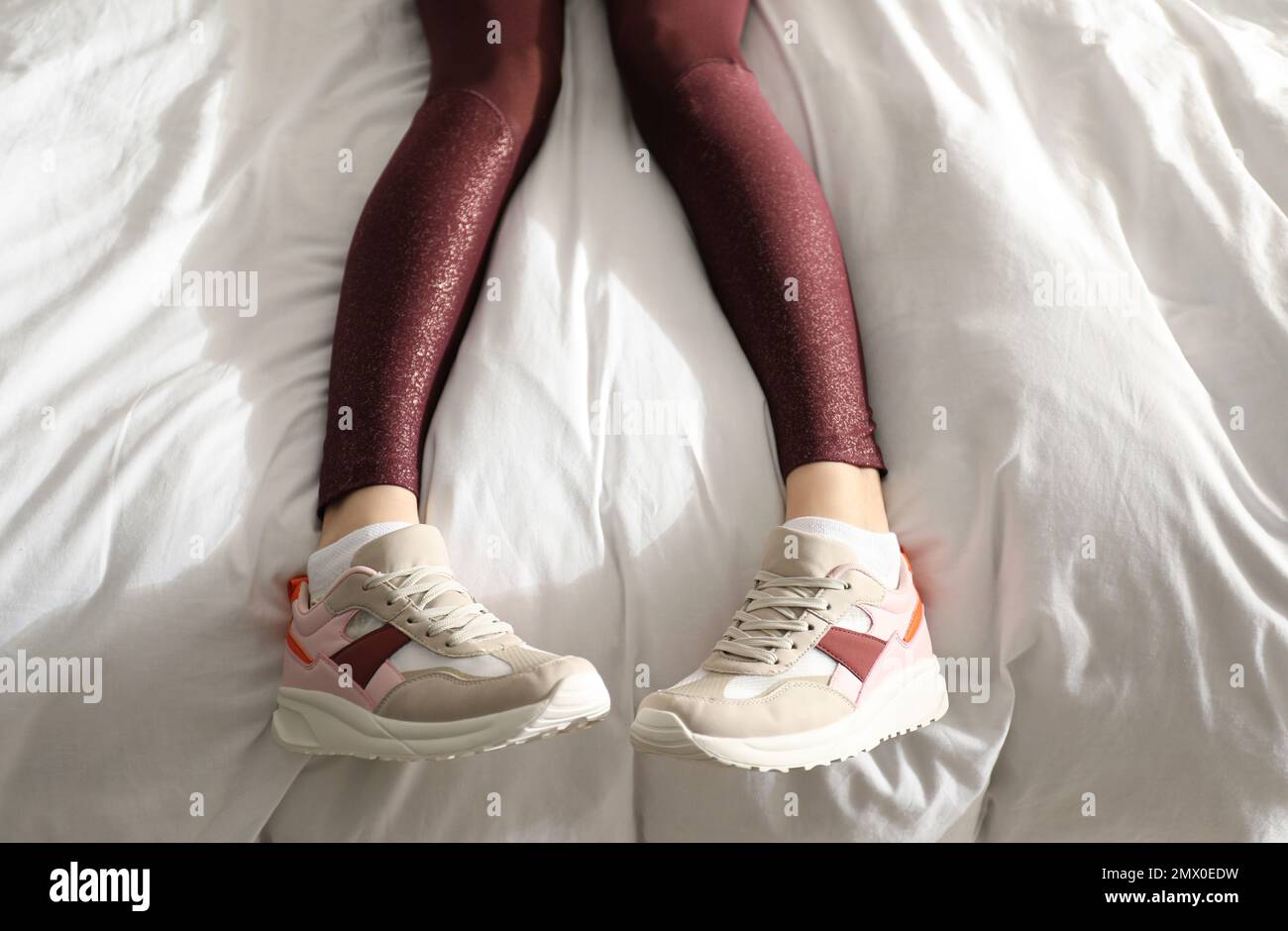 Lazy young woman sleeping on bed instead of morning training, top view