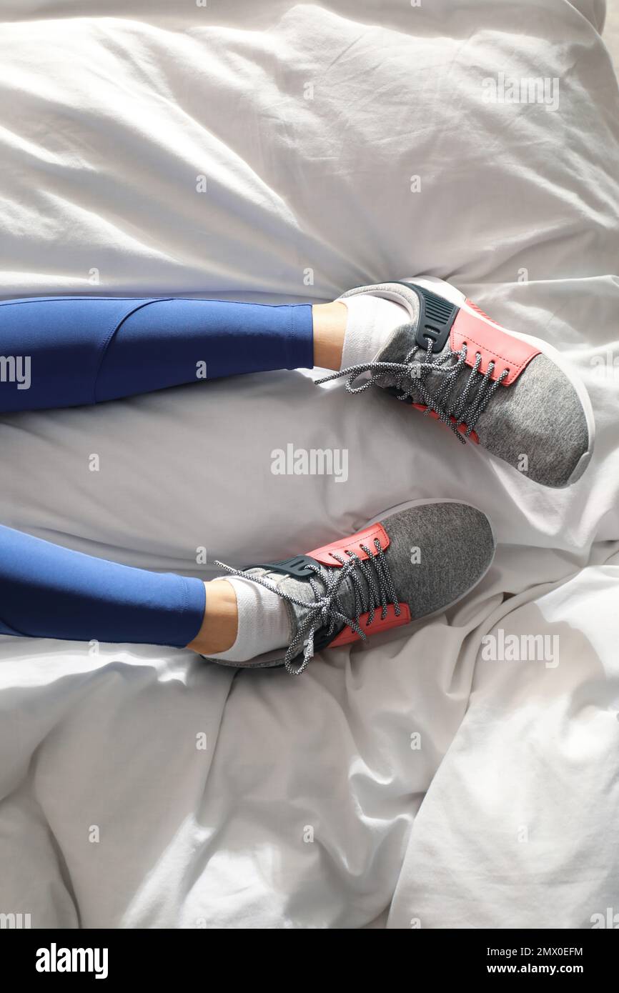 Lazy young woman sleeping on bed instead of morning training, top view