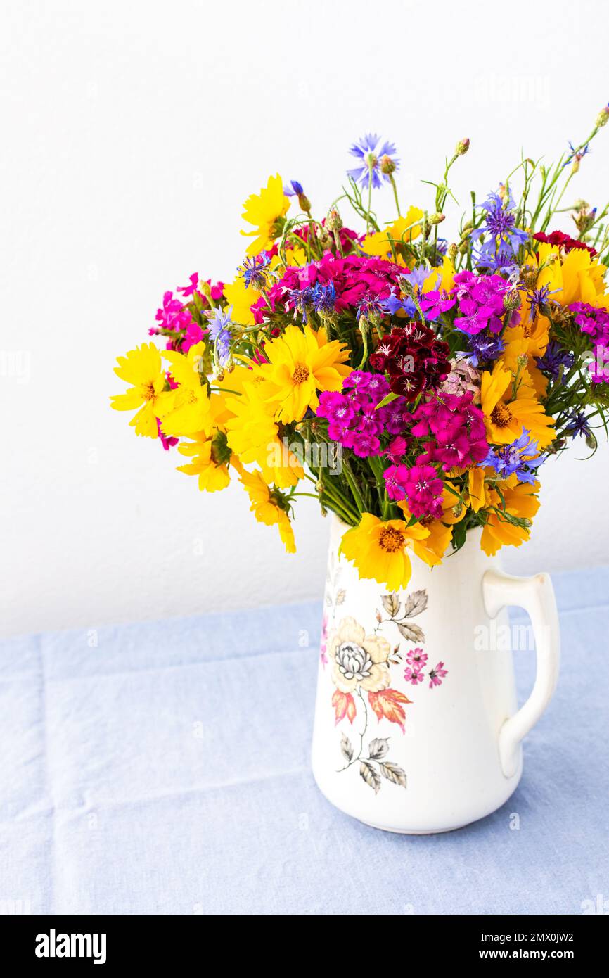 Beautiful summer bouquet of carnations, cornflowers and yellow chamomiles, part of home interior Stock Photo