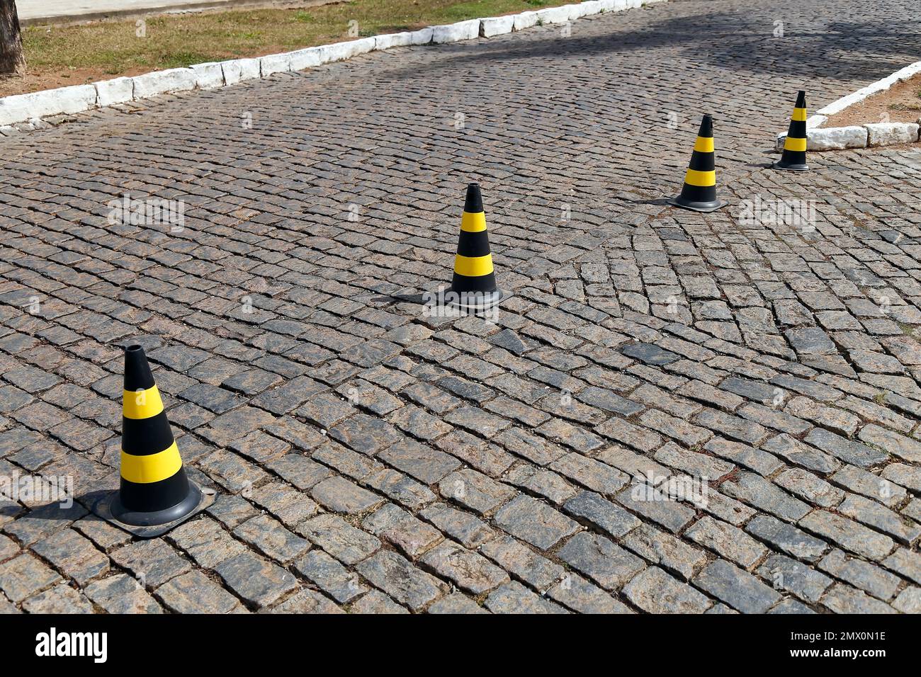 traffic signal cone yellow and black colors, hard plastic, on stone public road Stock Photo