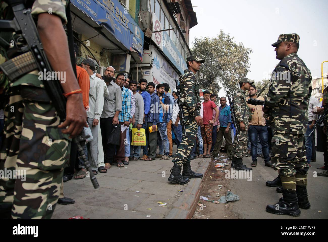 Indian paramilitary soldiers stand guard as people wait in a queue to  deposit and exchange discontinued currency notes outside a bank in New  Delhi, India, Wednesday, Nov. 16, 2016. This is just