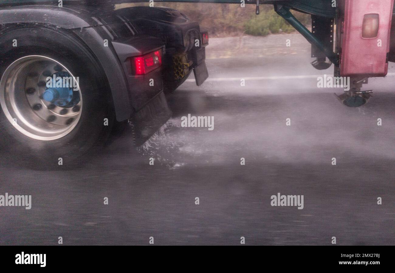 Truck wheels splashing water on road. Bad-weather driving concept Stock Photo