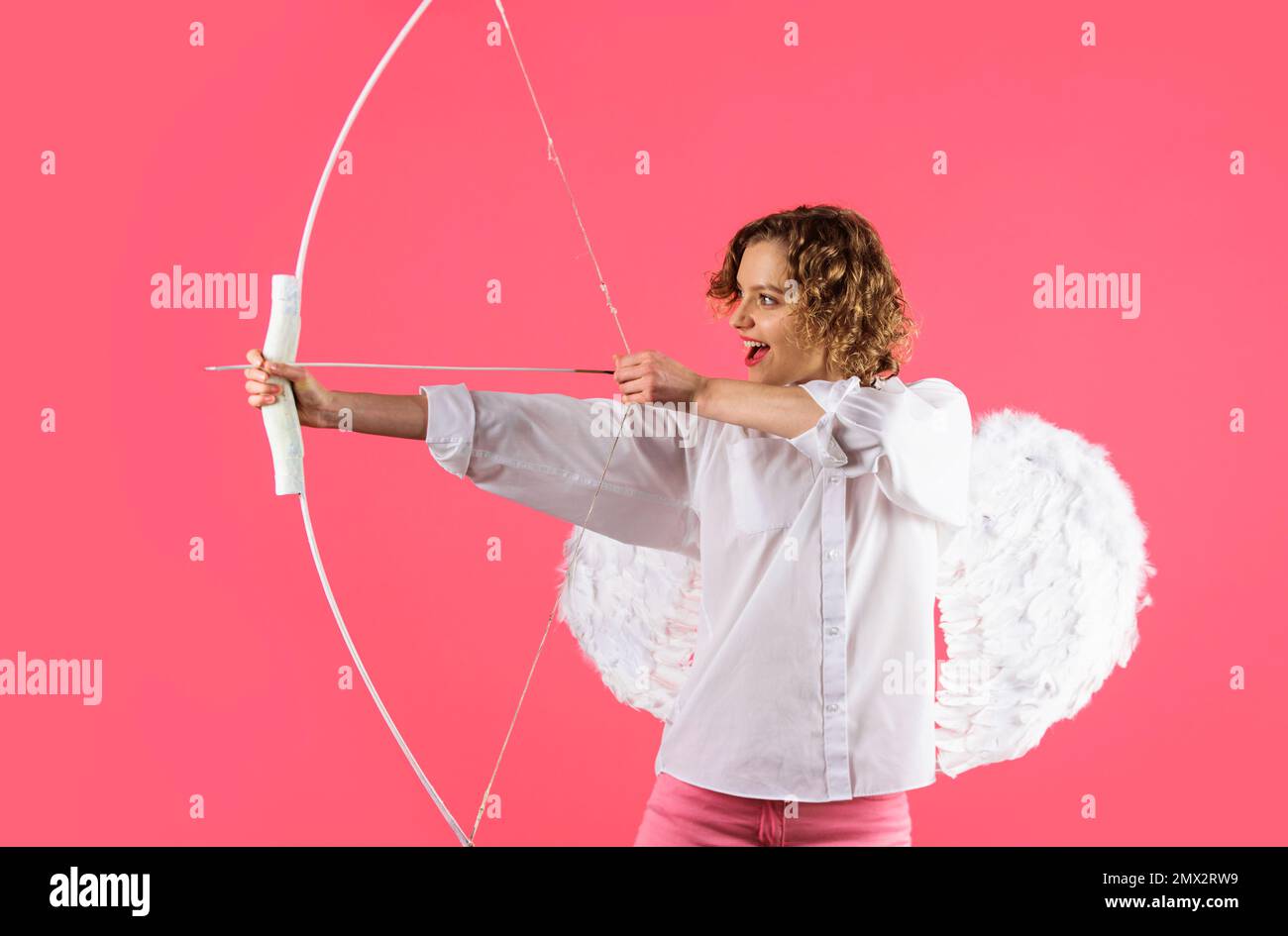 Female cupid shooting love arrow with bow. Valentines day celebration. Angel girl in white wings. Stock Photo