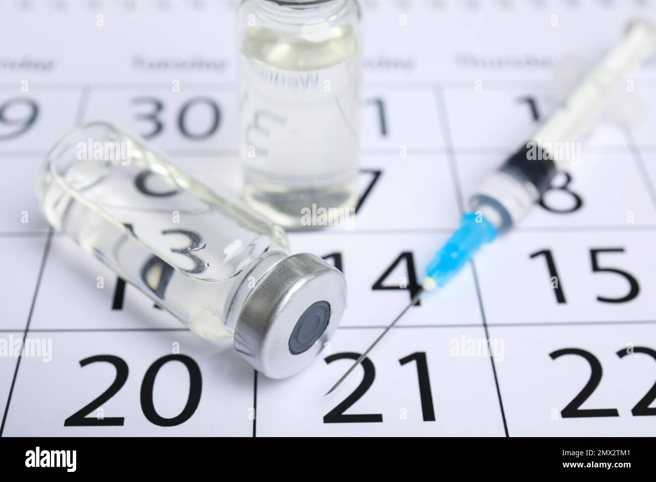 Vial and syringe on calendar, closeup. Vaccination and immunization ...