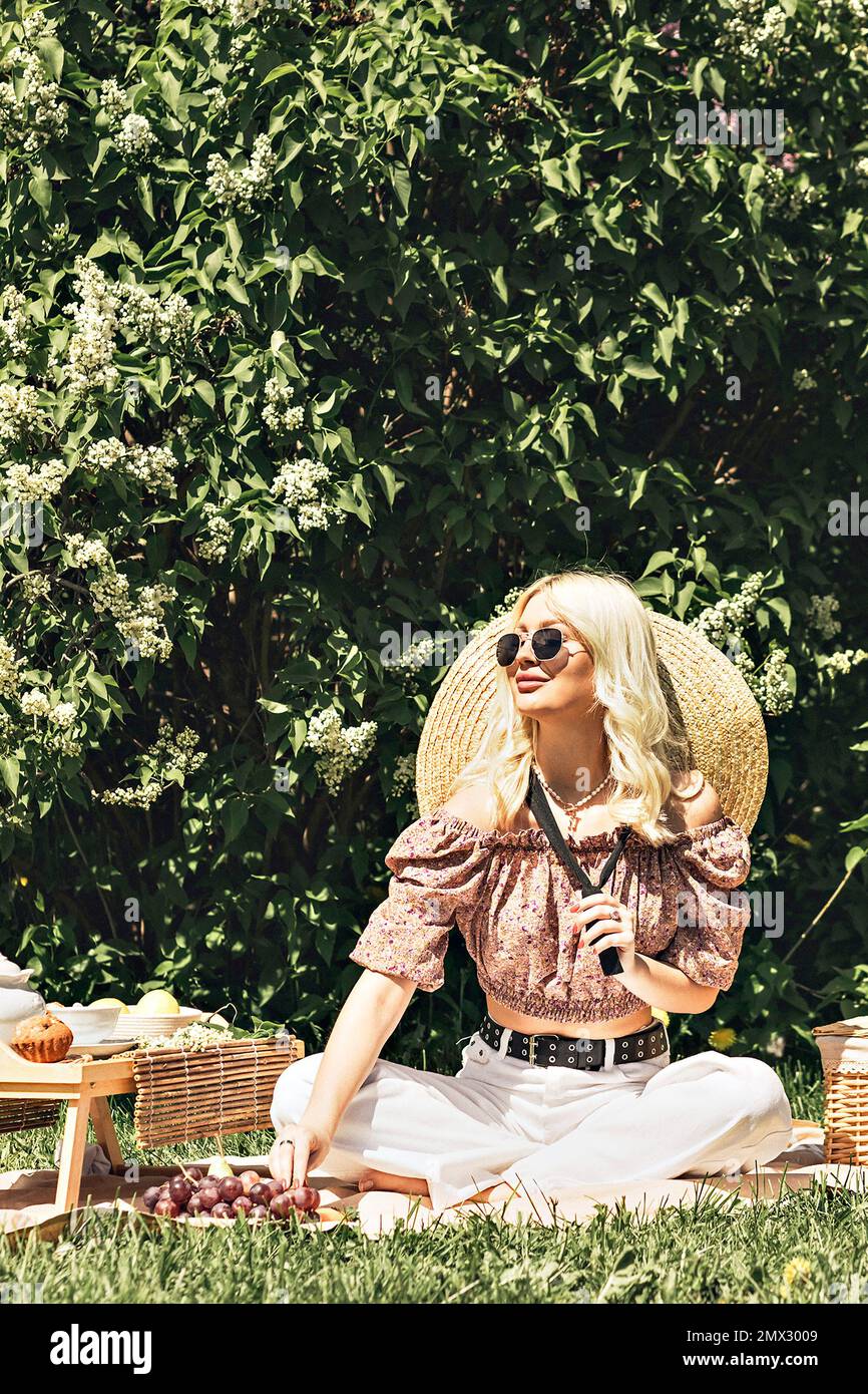 Photo of a charming pretty cute blonde lady who is holding a strawberry in her hand. Outdoor recreation,summer picnic. Stock Photo