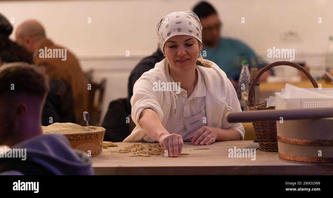 young white woman making fresh pasta in the window of a traditional Roman restaurant. rome