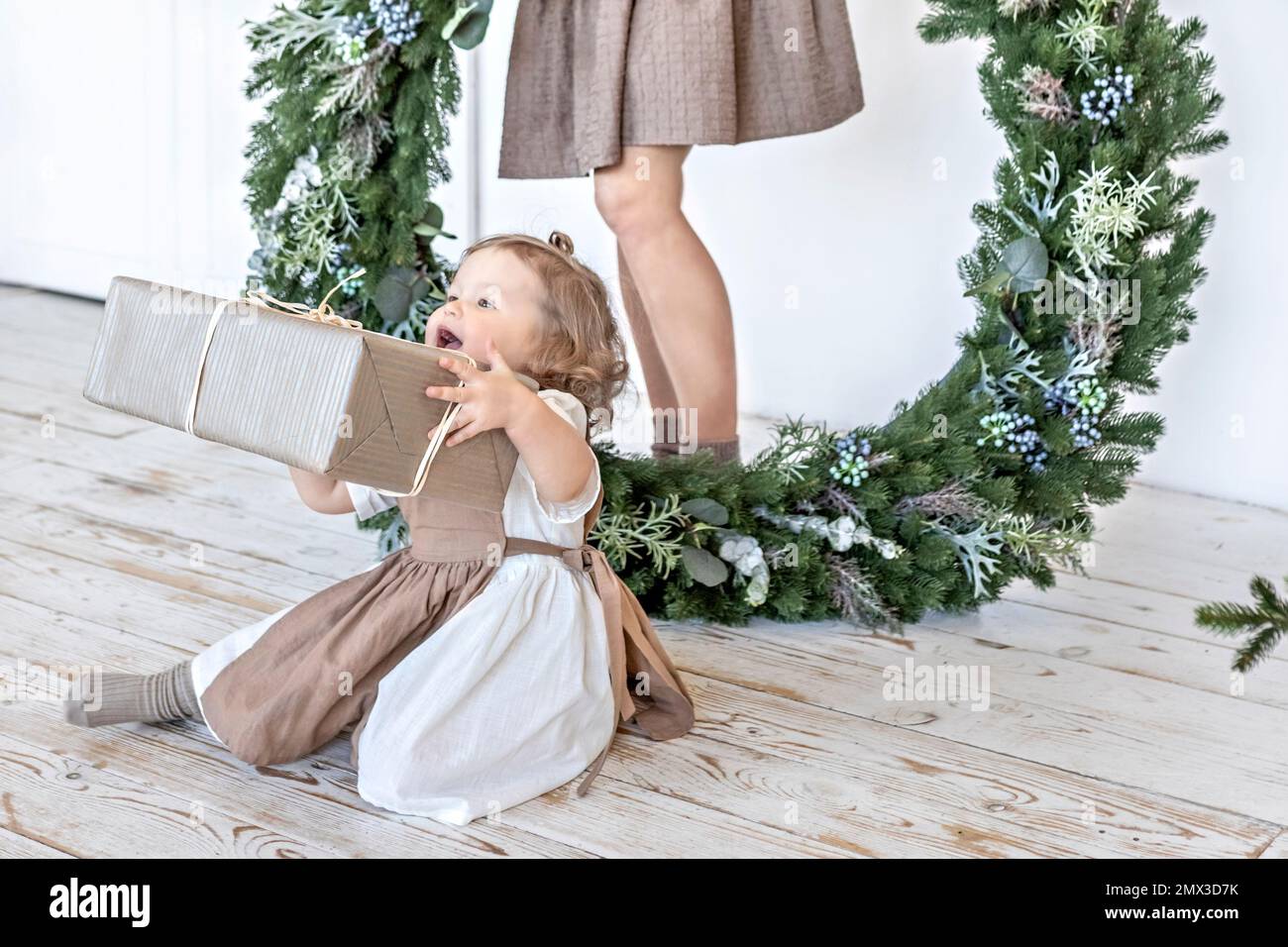 A young woman with blonde hair and a little daughter with a Christmas wreath. New Year's concept,Christmas decorations. Stock Photo