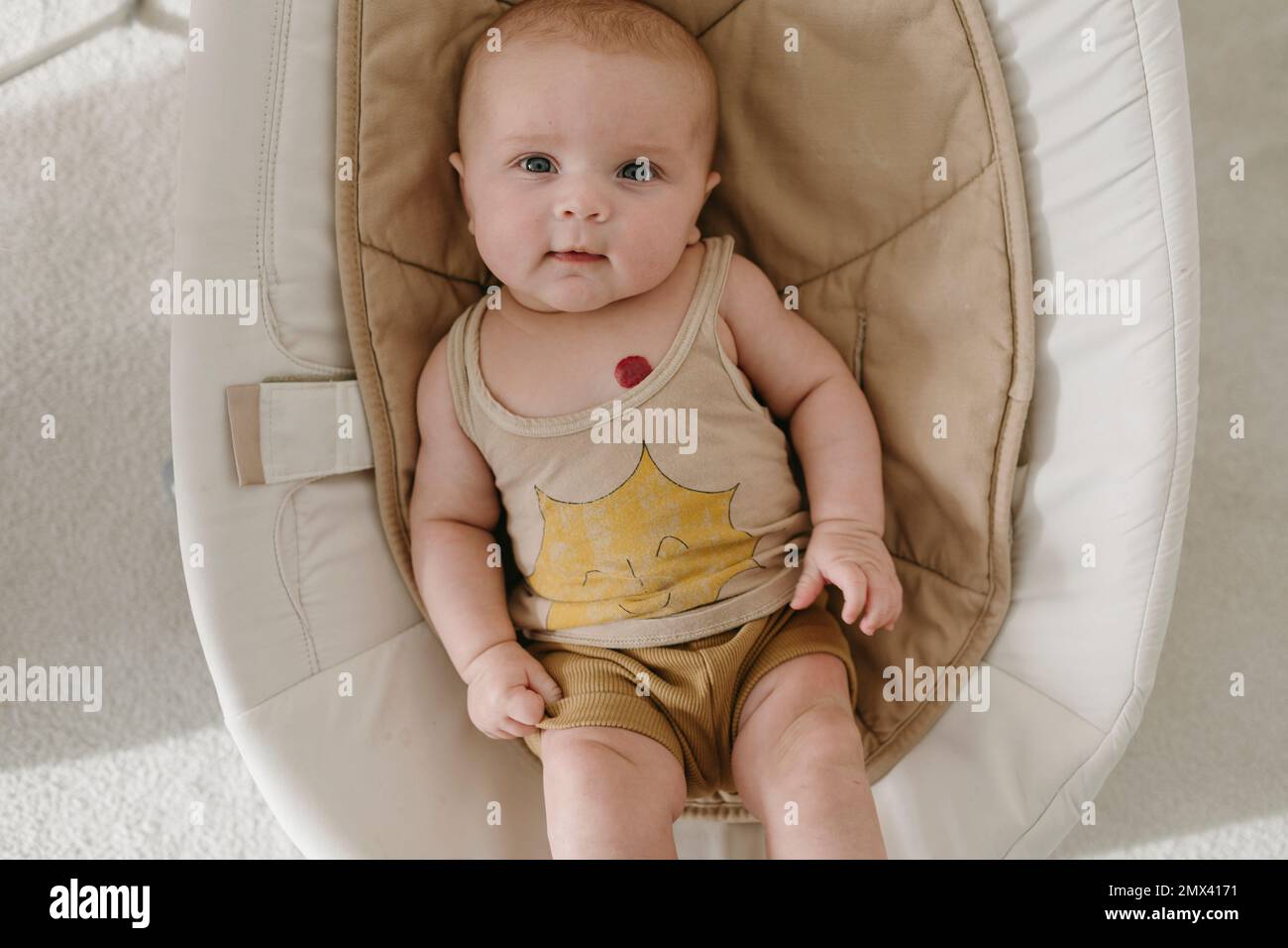 Baby in baby bouncer looking at camera Stock Photo