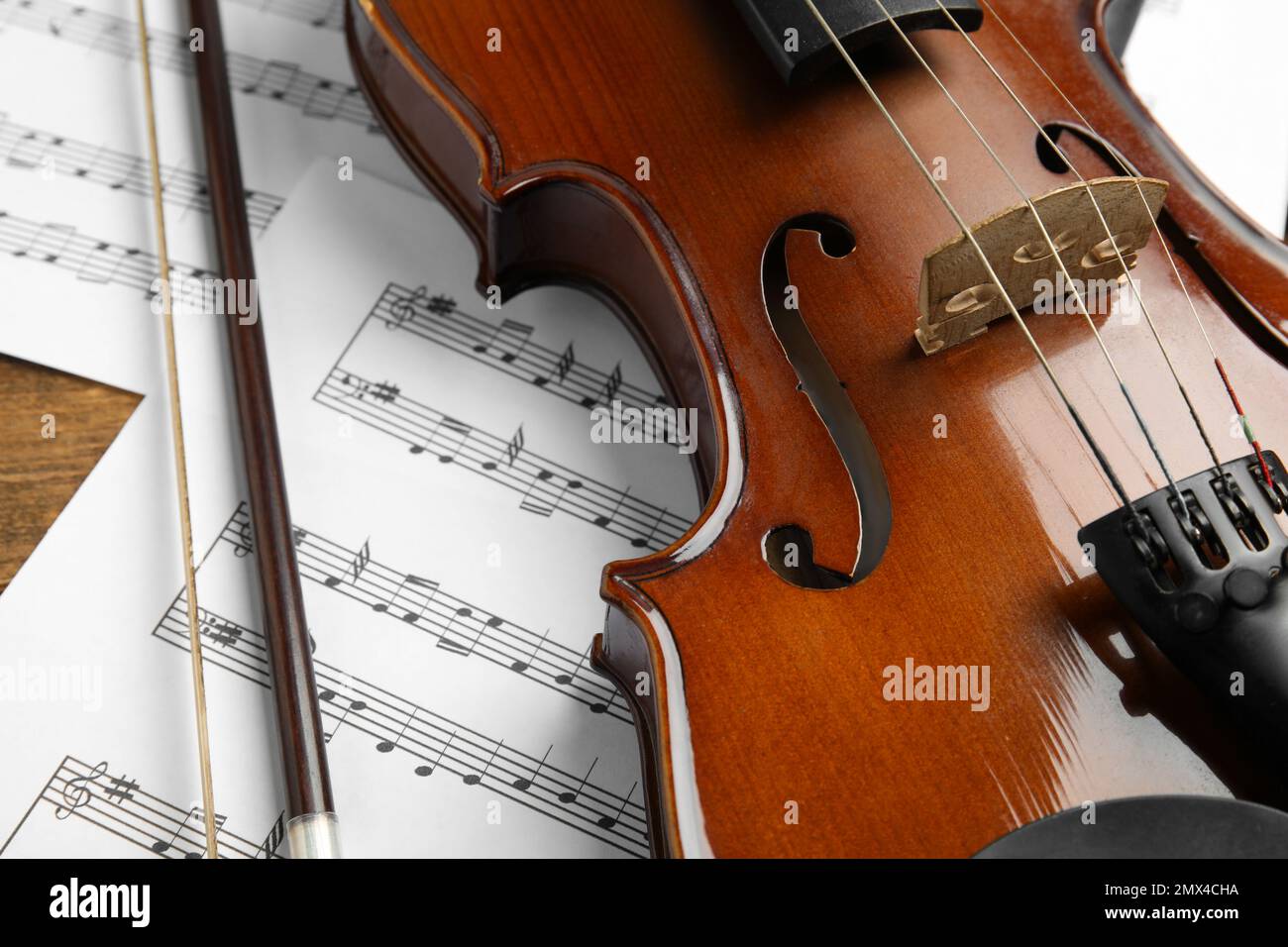 Beautiful violin, bow and note sheets on table, closeup Stock Photo