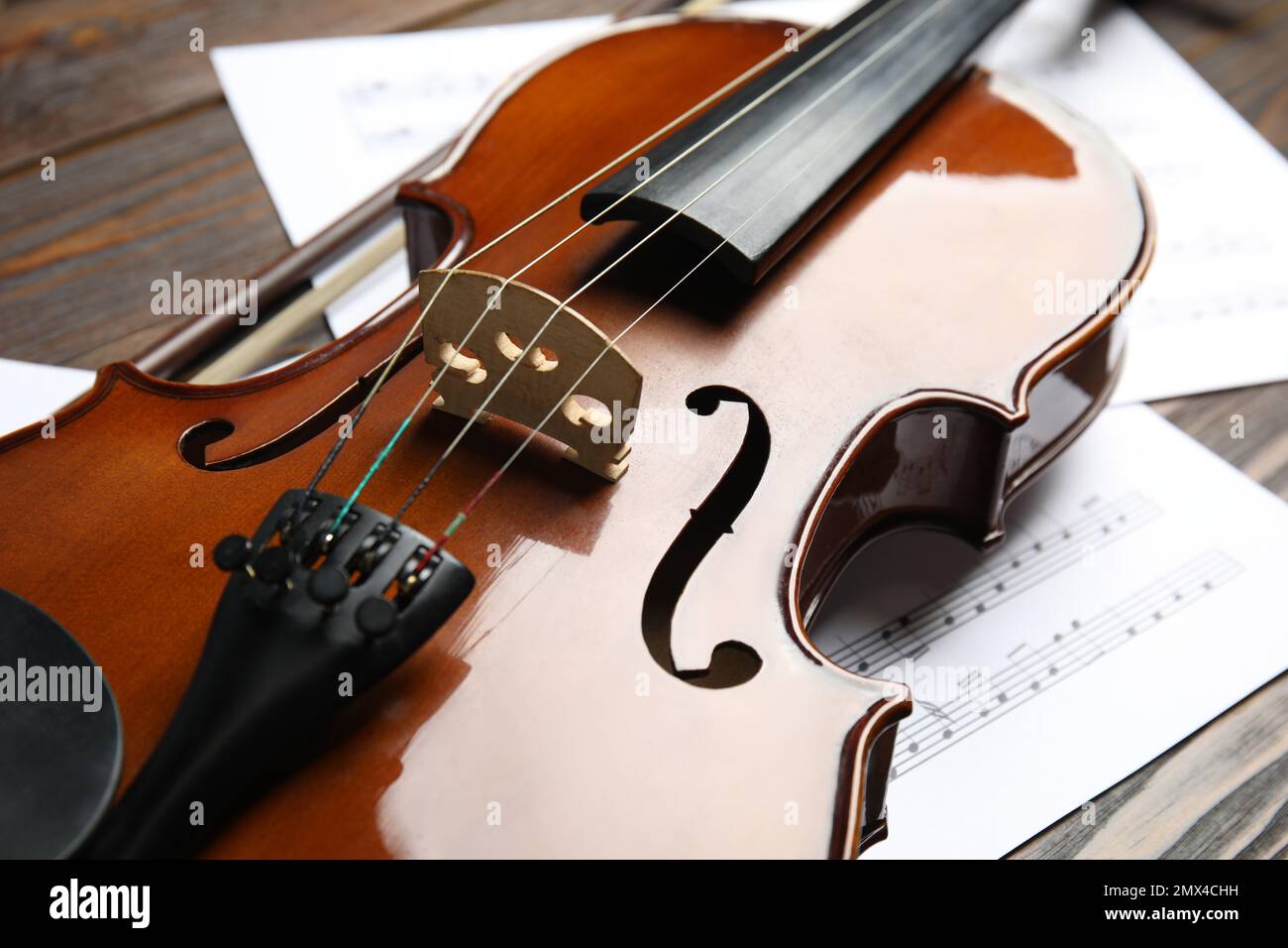 Beautiful violin, bow and note sheets on wooden table, closeup Stock Photo