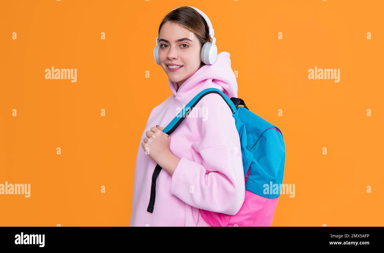 happy college student girl in headphones with backpack on yellow ...