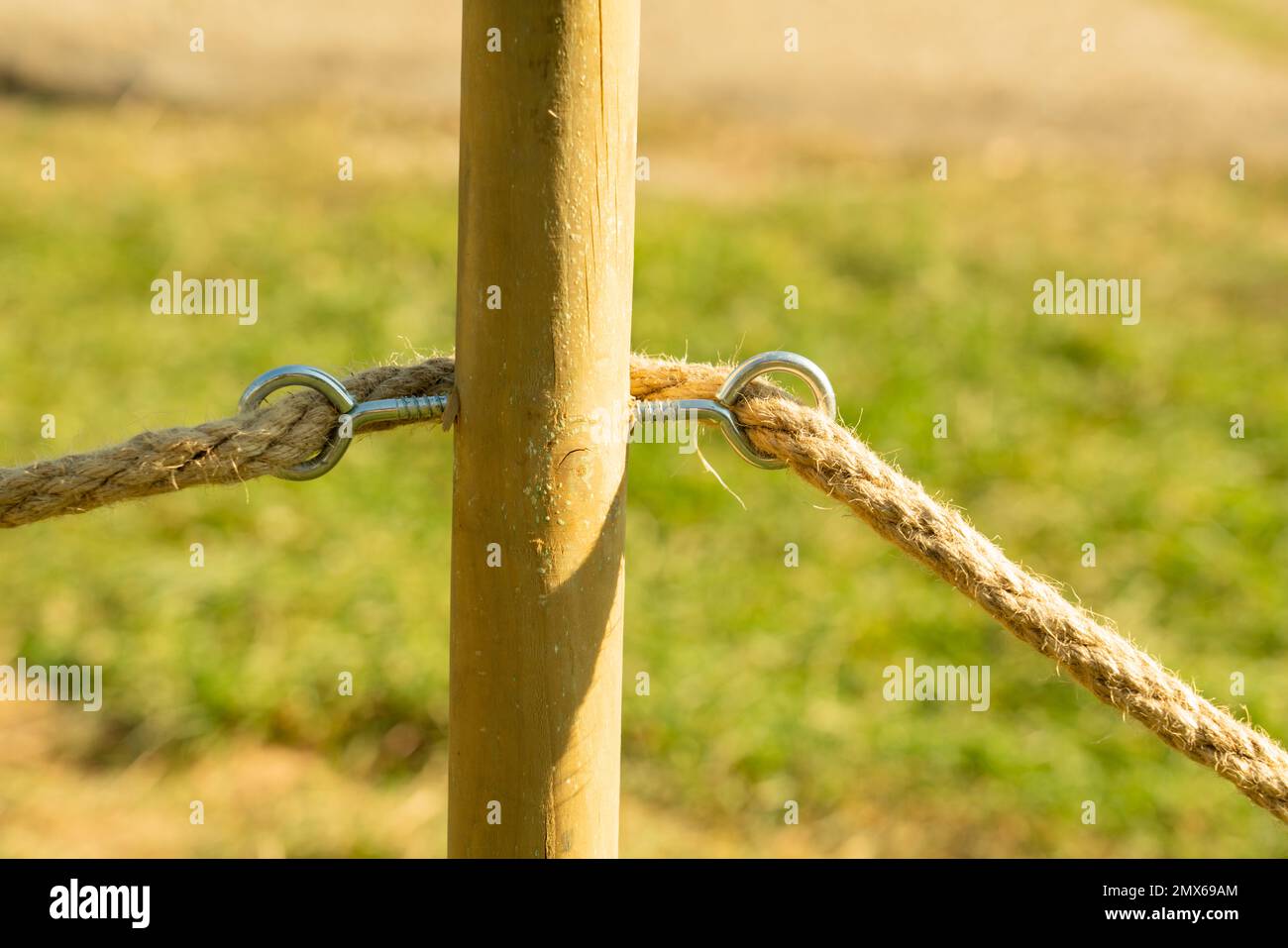 Close-up of wooden pole for delimitation with rope in outdoor nature stress-free relaxing park as leisure peaceful countryside travel concept Stock Photo