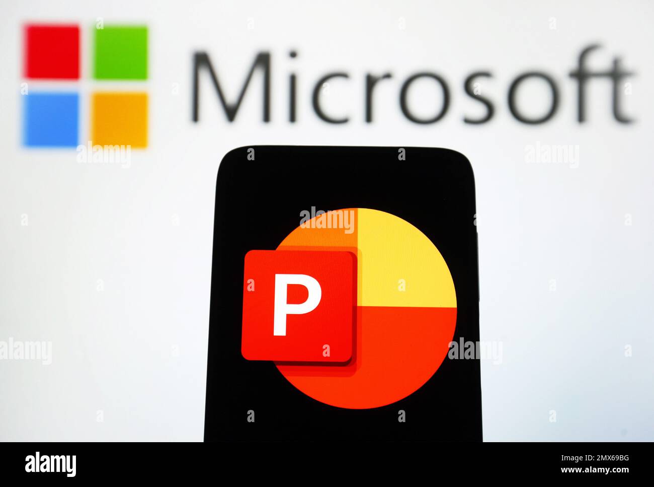 In this photo illustration, Microsoft PowerPoint logo of a software is seen on a smartphone sceen and Microsoft logo on a pc screen. Stock Photo
