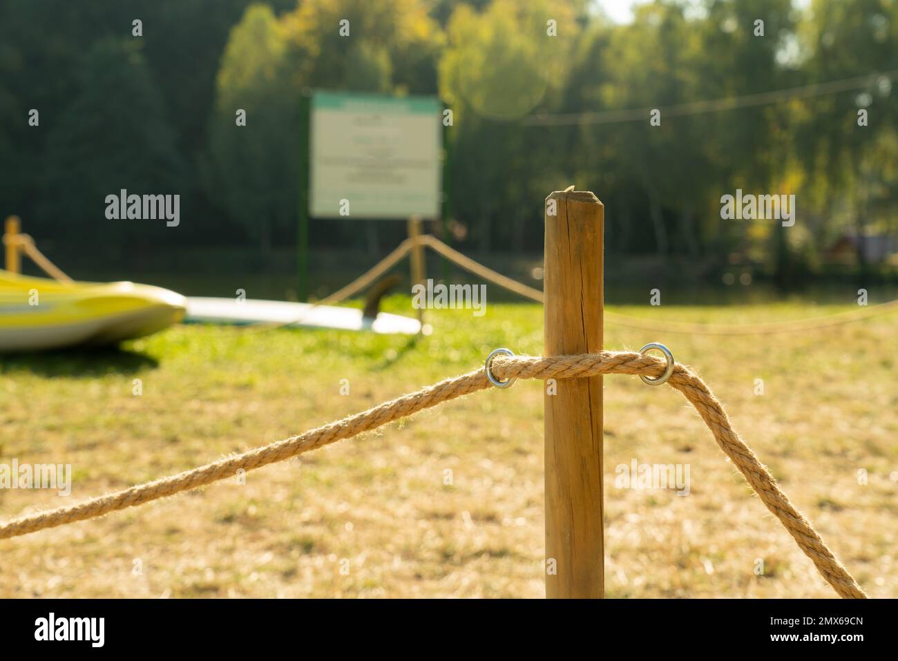 Wooden pole with rope for space delimitation with green natural grass ...