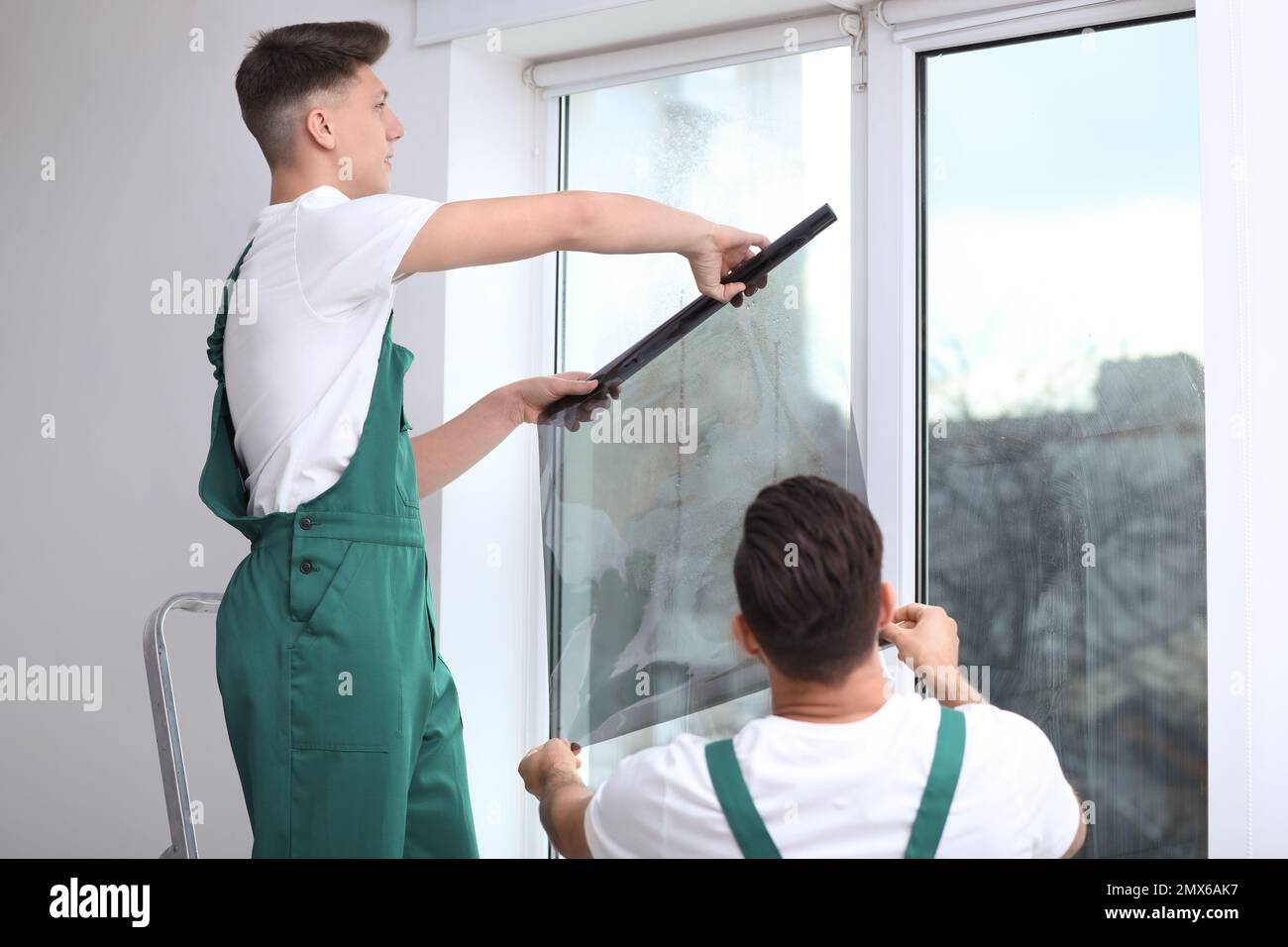 Professional workers tinting window with foil indoors Stock Photo