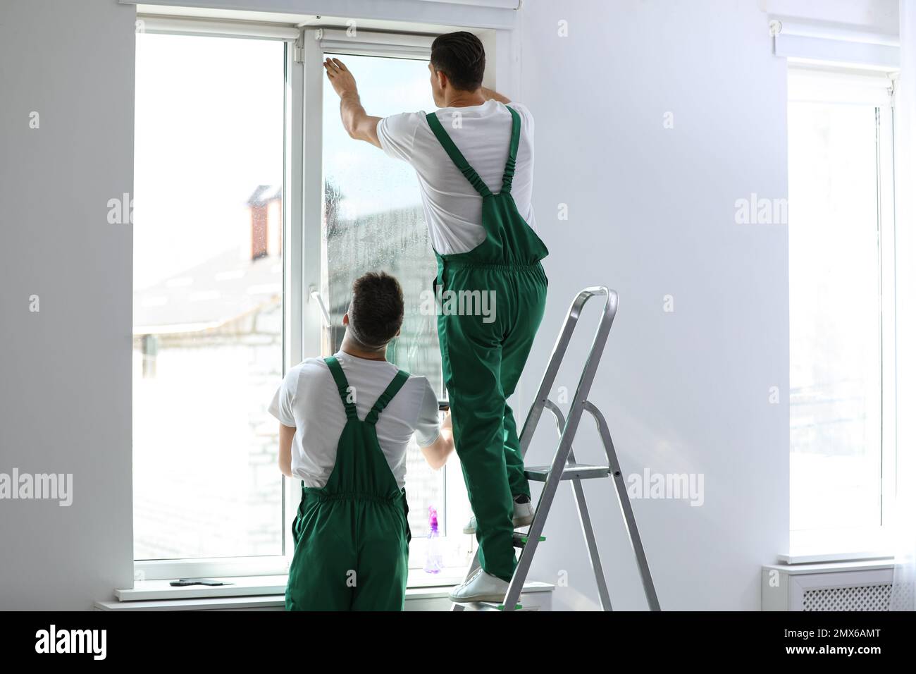 Professional workers tinting window with foil indoors Stock Photo
