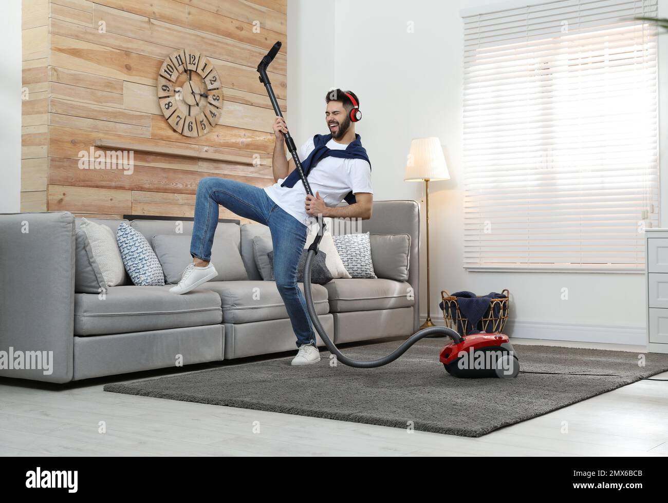 Young man having fun while vacuuming at home Stock Photo