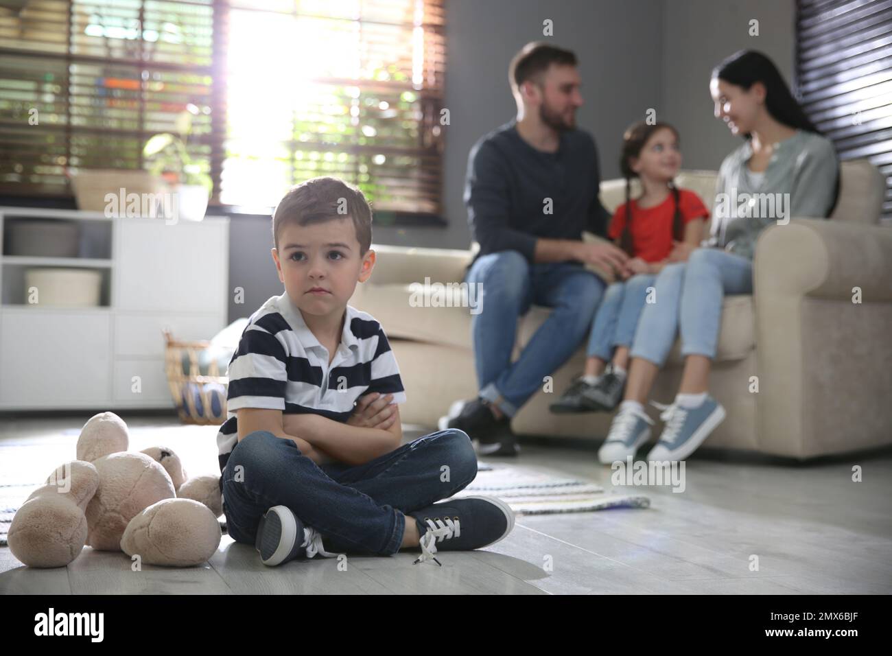 Unhappy little boy feeling jealous while parents spending time with his