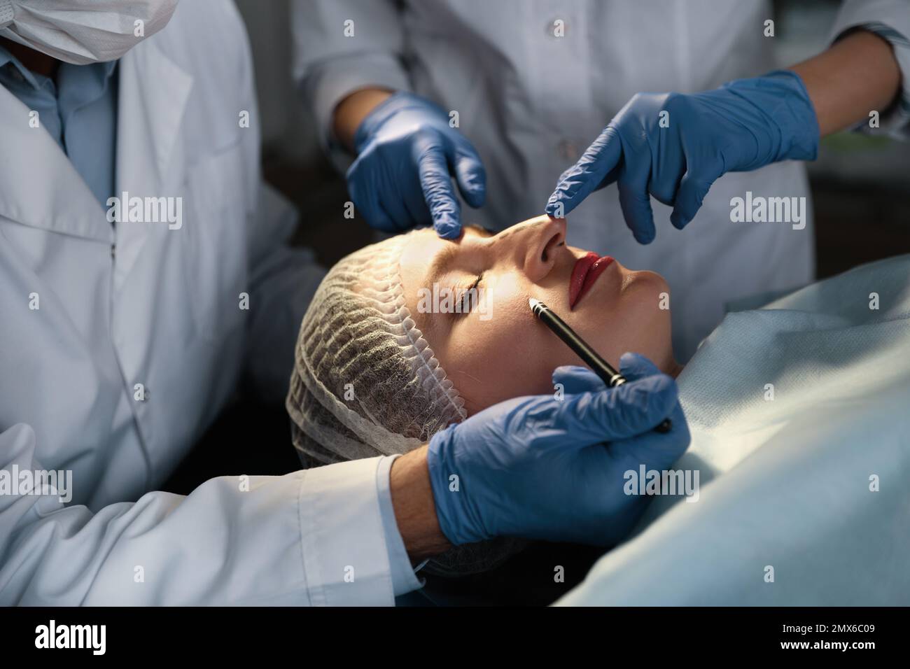 Doctor and nurse preparing female patient for cosmetic surgery in clinic Stock Photo