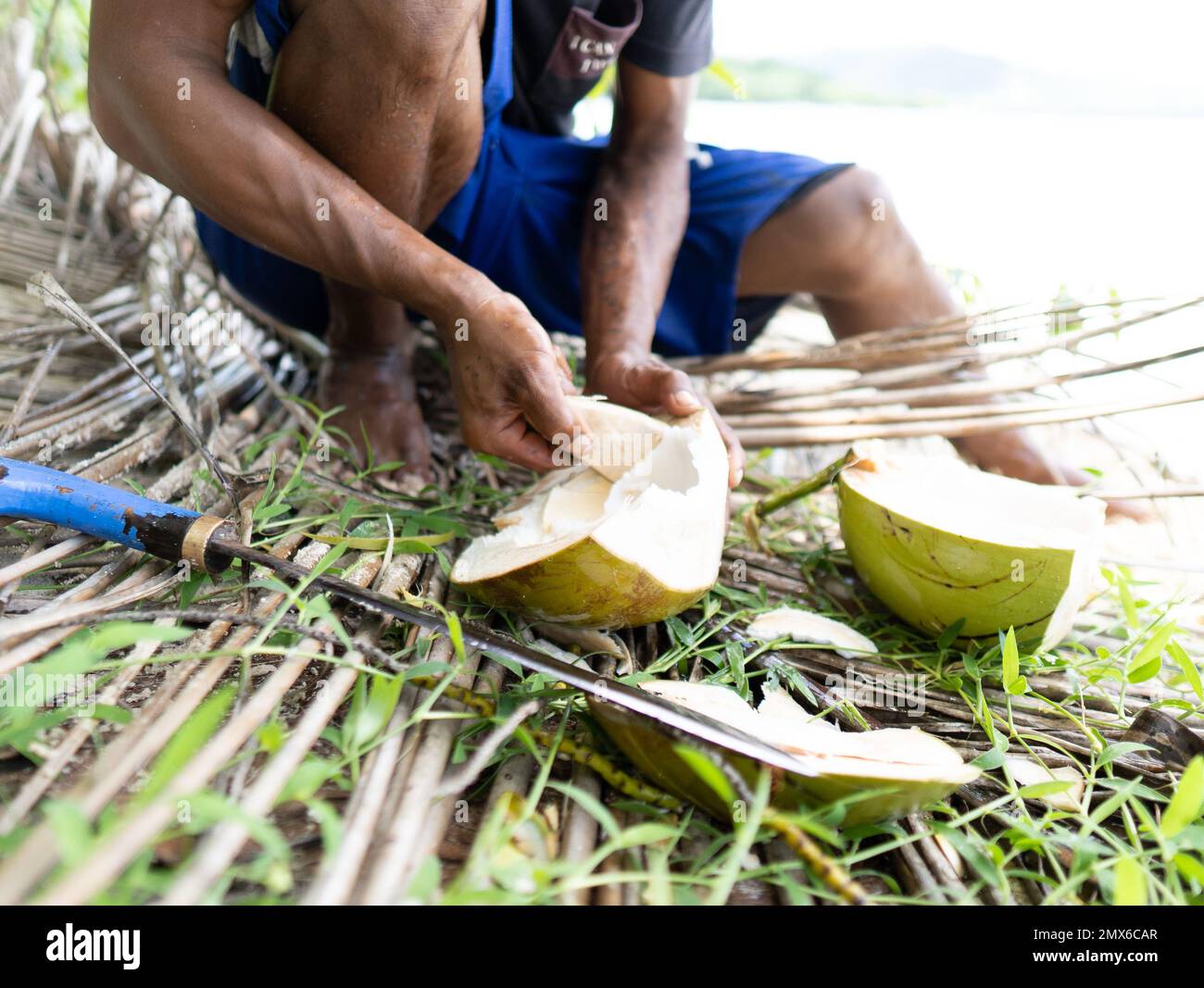 detail of the hands of a young Filipino fisherman eating coconut on a