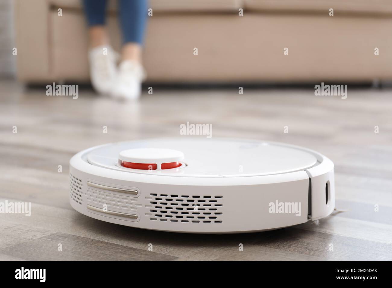 Woman resting while robotic vacuum cleaner doing her work at home Stock Photo