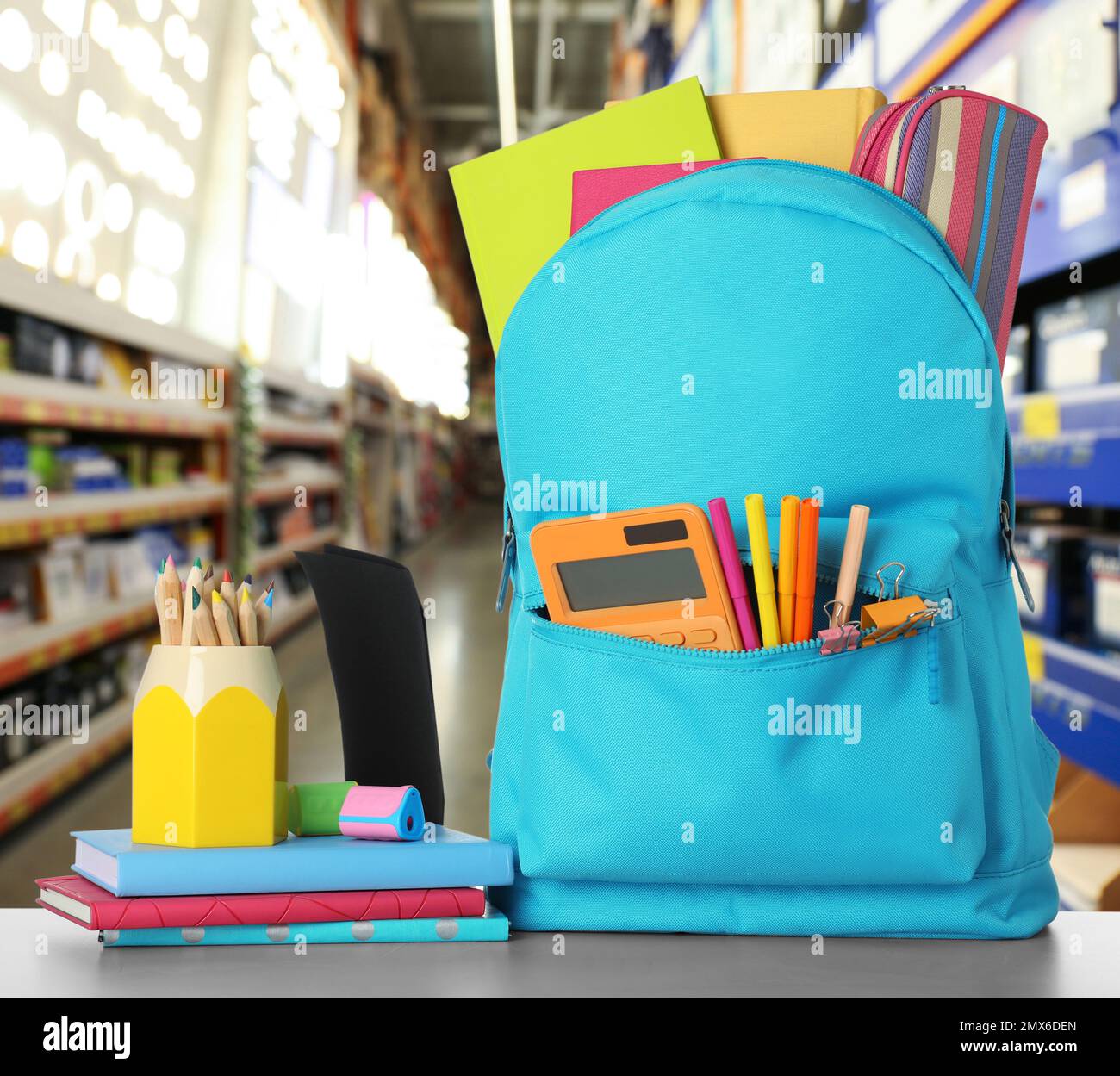 Bright backpack with school stationery on table in shopping mall Stock