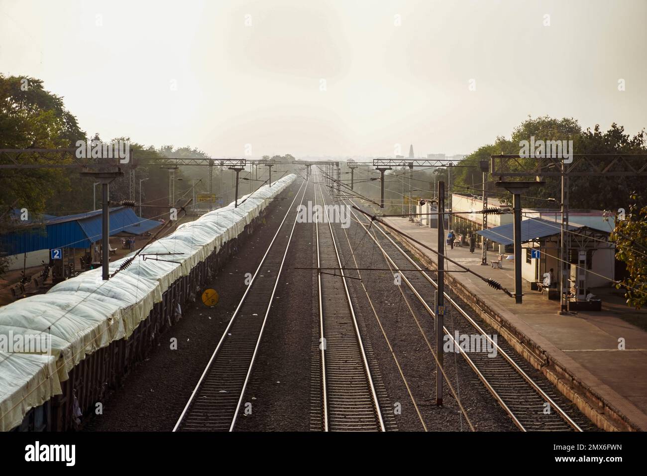 in india a loader train is standing in railway station at left side and a view of empty train metal tracks, a photo from top of bridge Stock Photo