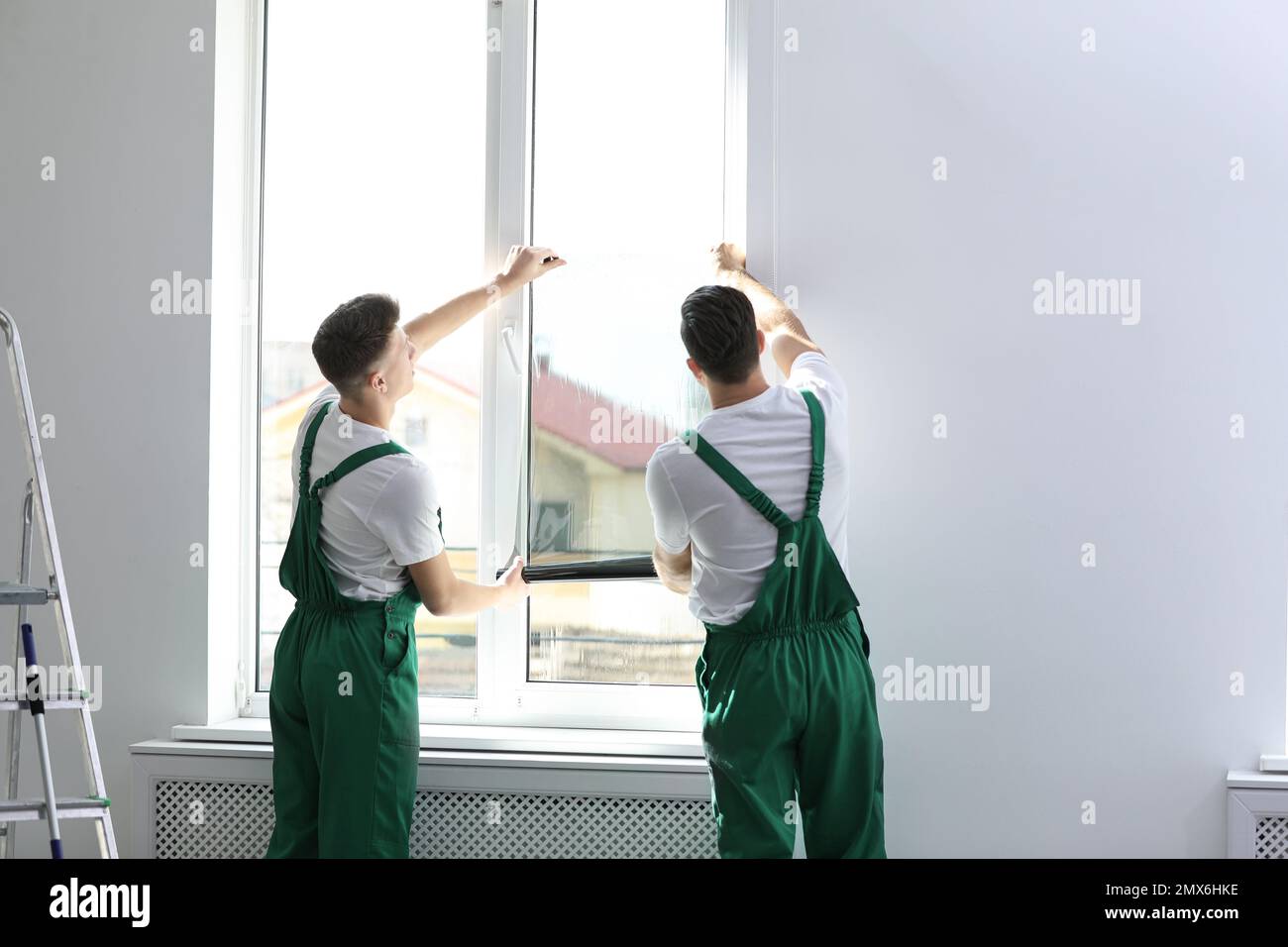 Professional workers tinting window with foil indoors Stock Photo