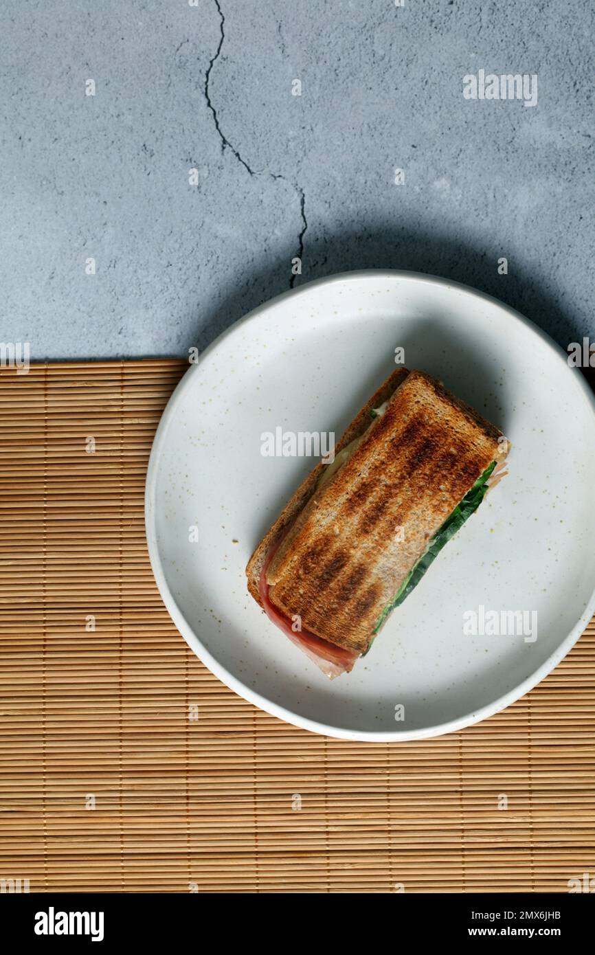 Toasted sandwich with lettuce,ham and cheese on a white plate. Stock Photo
