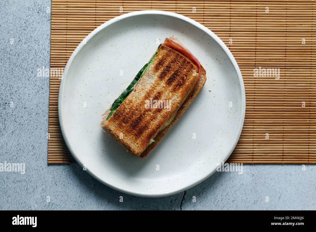 Toasted sandwich with lettuce,ham and cheese on a white plate. Stock Photo