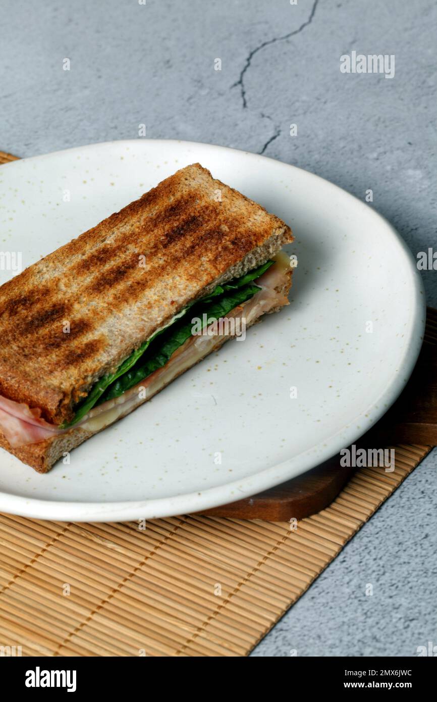Toasted sandwich with lettuce ham and cheese on a white plate. Stock Photo