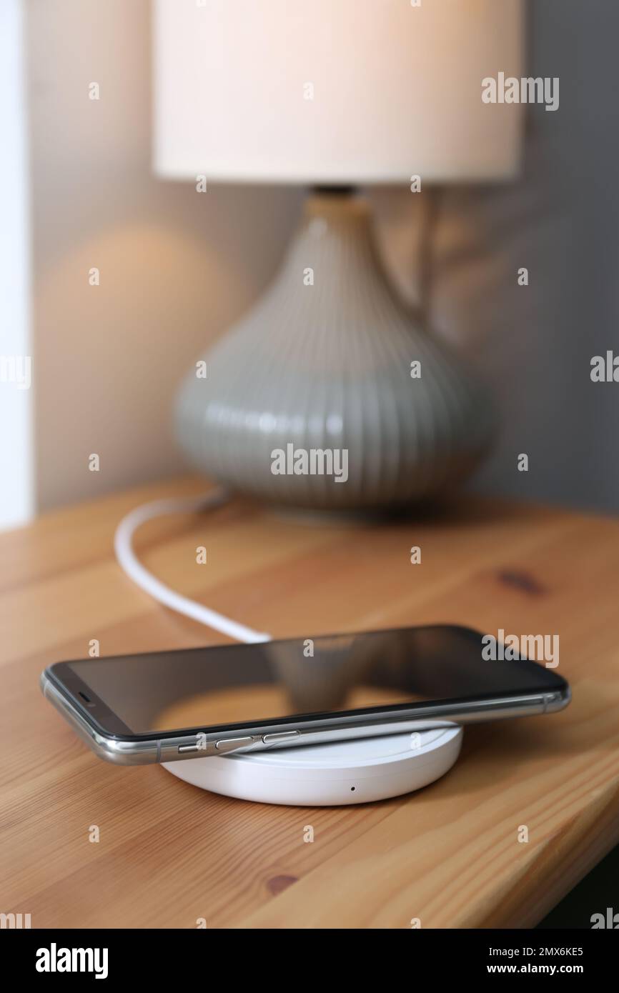 Smartphone charging on wireless pad in room Stock Photo
